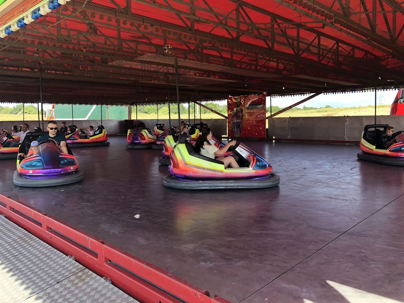 Bright yellow, orange and purple dodgem cars crossing the steel track beneath the pickup grid