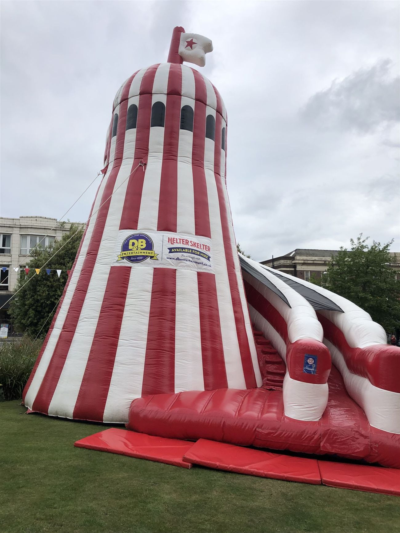 The helter skelter tower set up for a town-centre event, showing its full striped height, arched windows and slide lanes