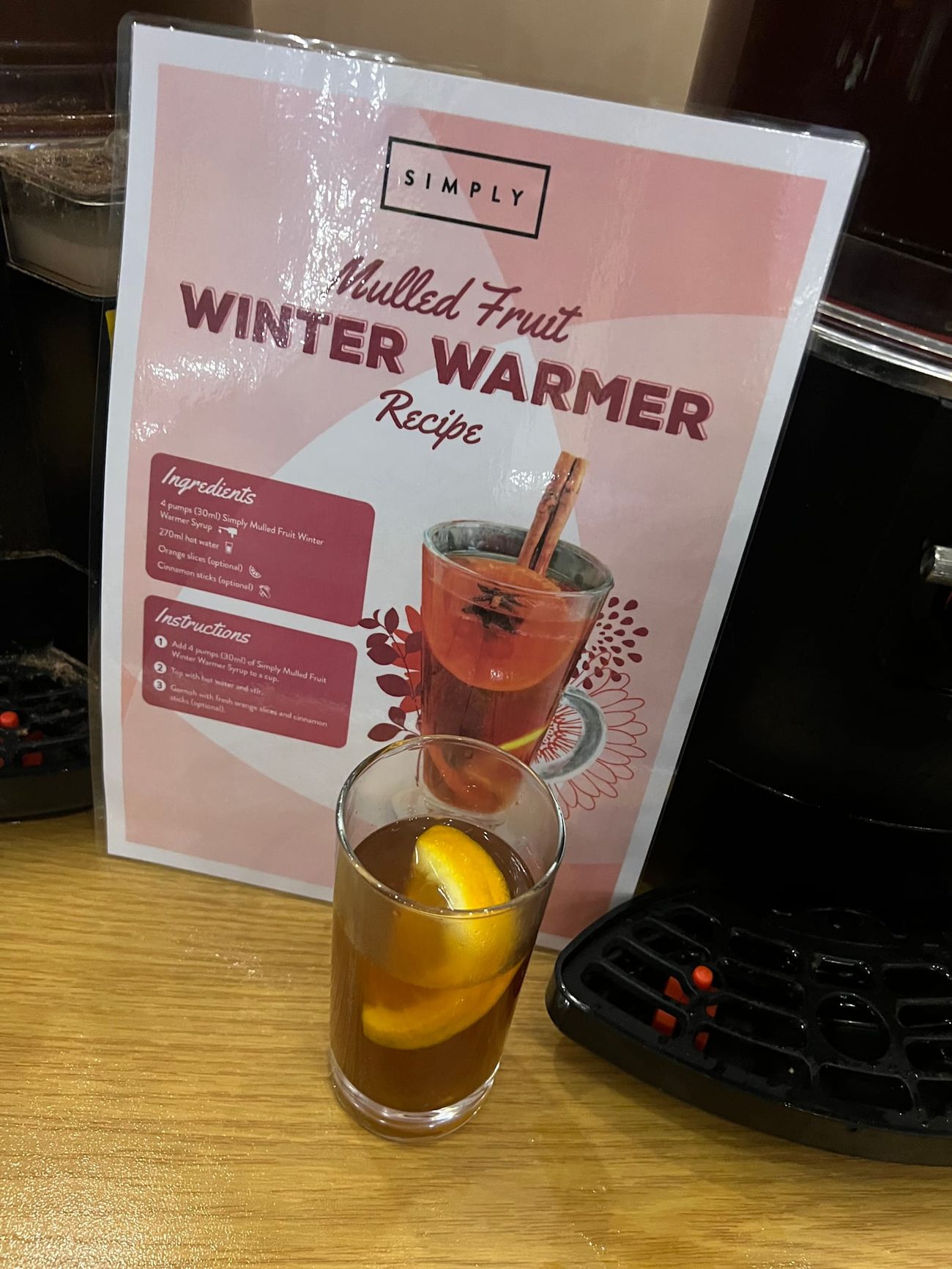 A glass of mulled wine beside the recipe sign, showing the drink ready to serve