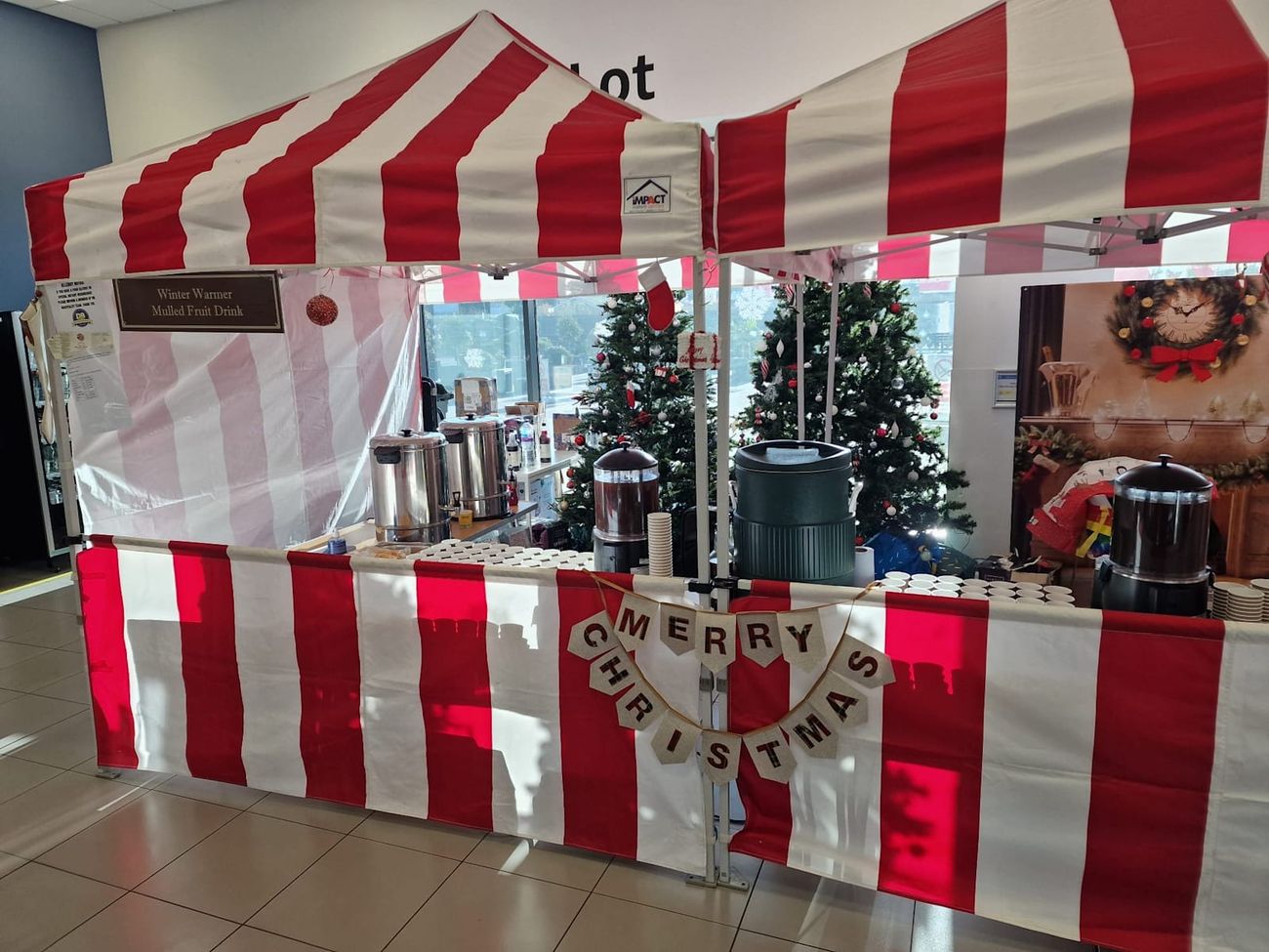 Mulled wine stall under its red and white striped canopy at an indoor event